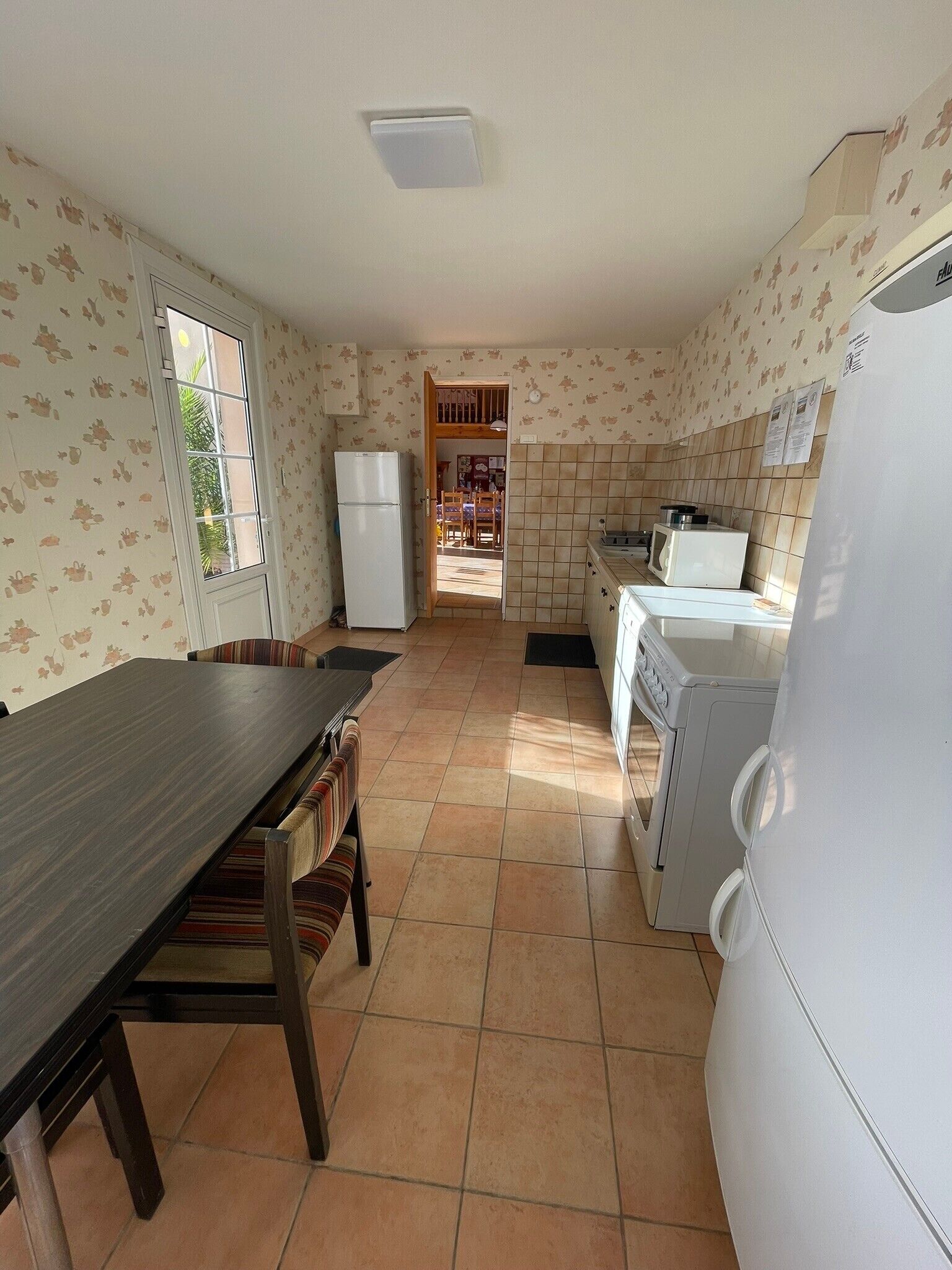 A compact kitchen with a dining area, a refrigerator, a washing machine, and a tiled backsplash.