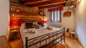 Een slaapkamer met houten lambrisering, een bed, een rode lamp, een raam en een radiator.