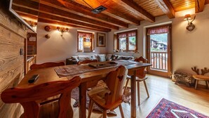 Een houten eettafel met stoelen, een bank en een raam met uitzicht.