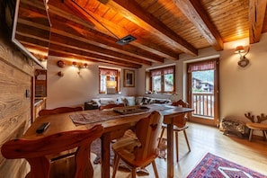 Une table à manger en bois, des chaises, un canapé et une fenêtre donnant sur un beau paysage.