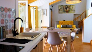 Una cocina moderna con un lavamanos, una mesa de comedor y sillas. Una escalera conduce a otro nivel.