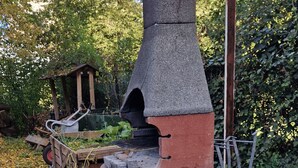 Uma mesa de bilhar com moldura verde e bolas vermelhas, uma chaminé de pedra e um carrinho de madeira com ferramentas.