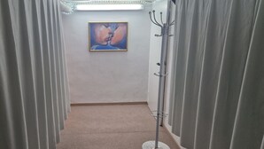Un pasillo con cortinas blancas, un cuadro enmarcado en la pared y un perchero.