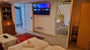 Habitación de hotel con una cama, una mesita pequeña, un televisor montado en la pared, un armario y una puerta que da a un balcón.