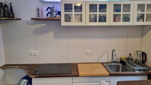 Una cocina compacta con encimera de madera, lavabo integrado y armarios blancos.
