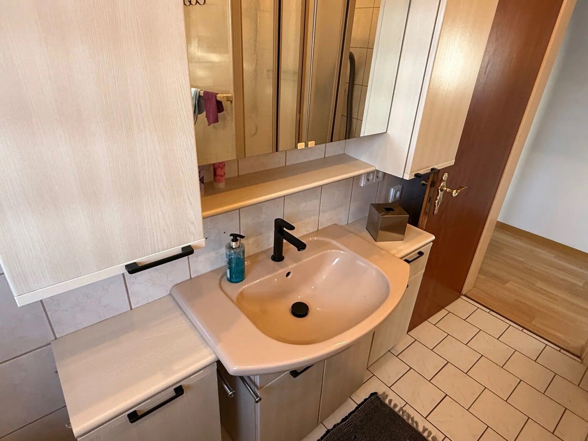 A bathroom with a sink, mirror, and a towel rack.