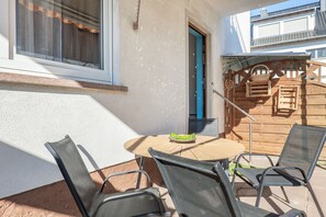 An outdoor patio with a round table and four chairs, a wooden door, and a metal gate leading to a deck. - Apartment 'Ferienwohnung Seus' with Wi-Fi (Dorfprozelten)