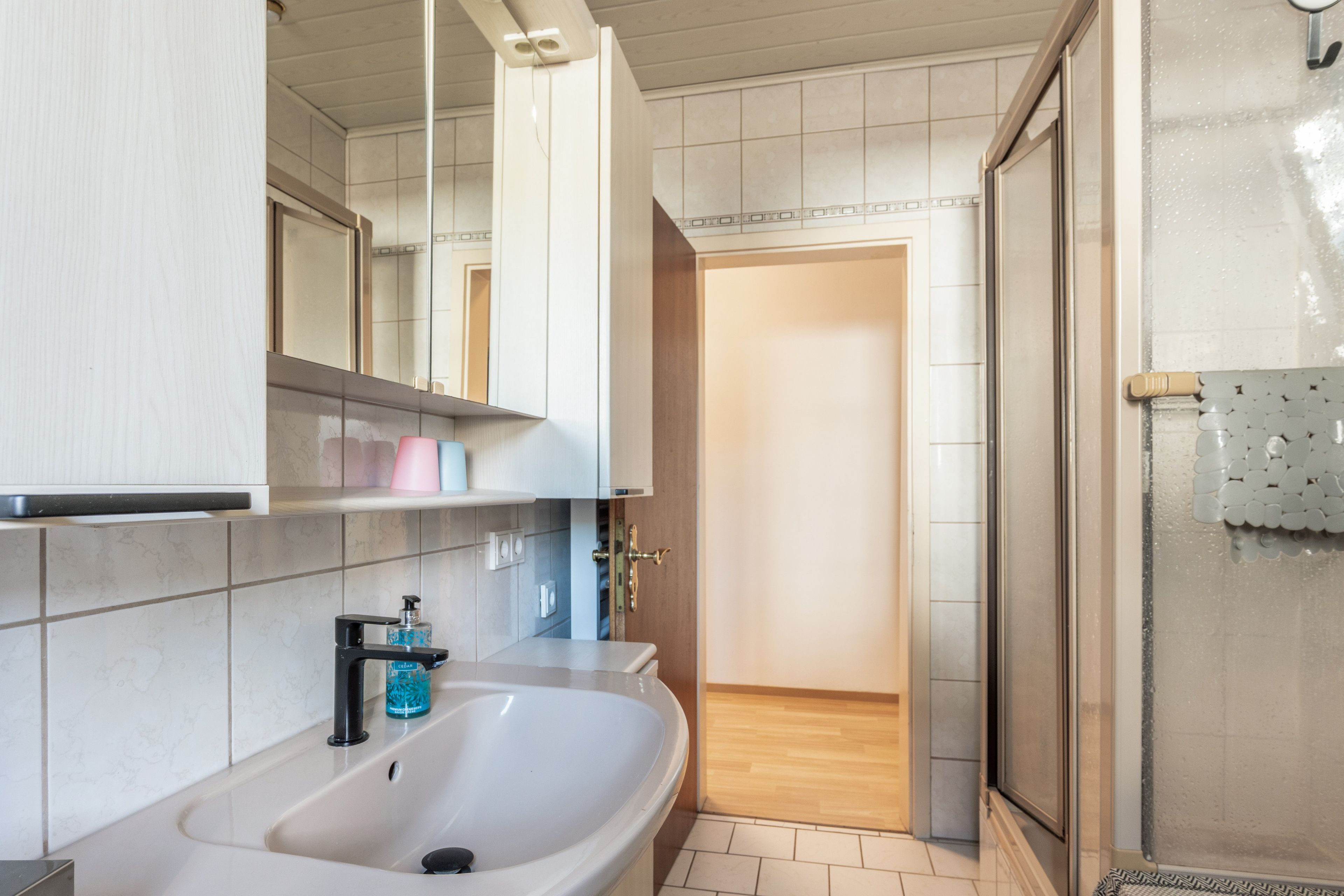 Ein Badezimmer mit Waschbecken, Spiegel und Duschbereich.