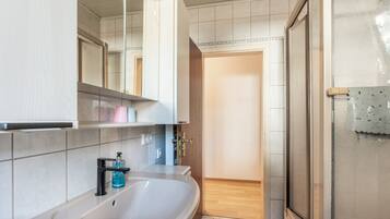 Ein Badezimmer mit Waschbecken, Spiegel und Duschbereich.