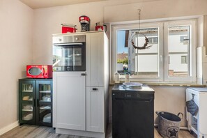 A compact kitchen with a white refrigerator, a black dishwasher, and a red vintage radio. - Apartment 'Ferienwohnung Seus' with Wi-Fi (Dorfprozelten)