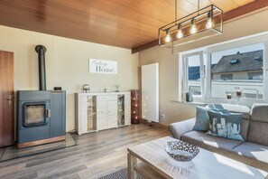 Una sala de estar moderna con una estufa de leña, un sofá con cojines estampados y un cartel que dice 'Feeling Home'.