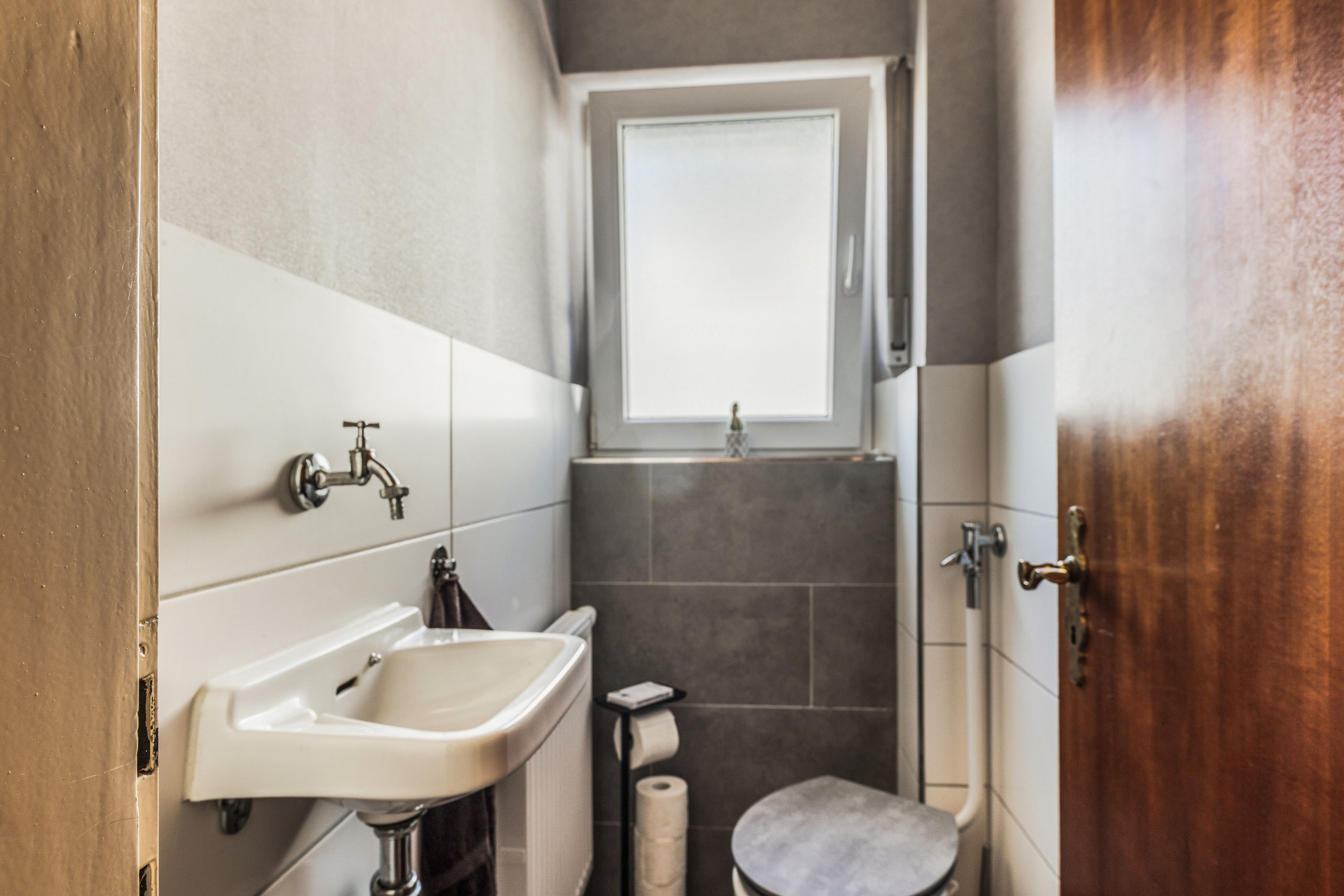 Une petite salle de bain comprenant un lavabo, des toilettes et une petite fenêtre située au-dessus de la douche.