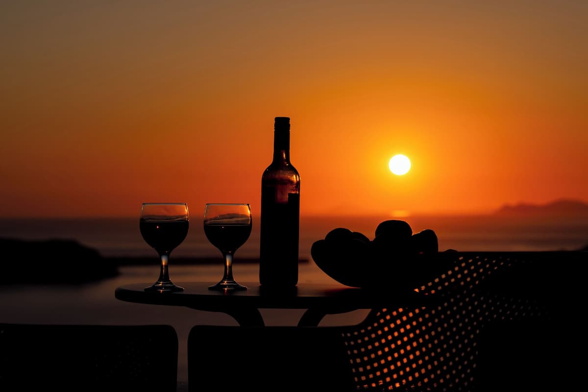 A sunset view with a bottle and glasses on a table.