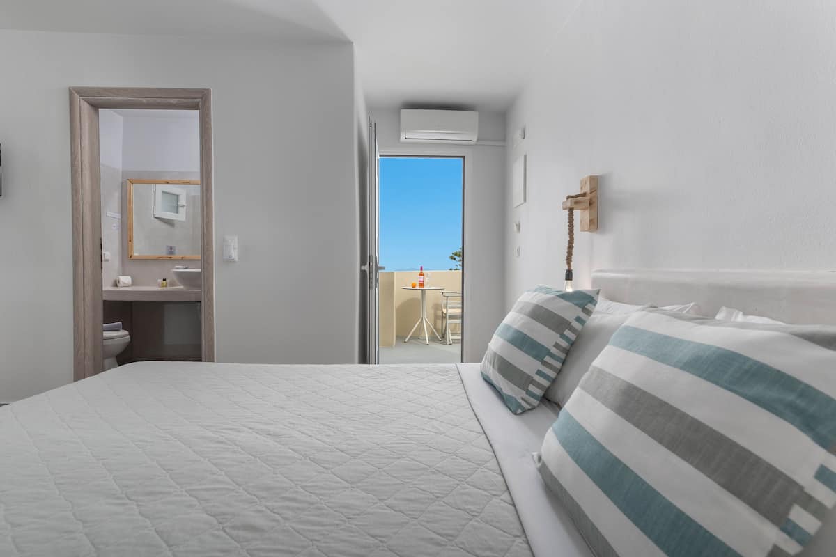 A hotel room with a bed, a bathroom, and a view of the outside.