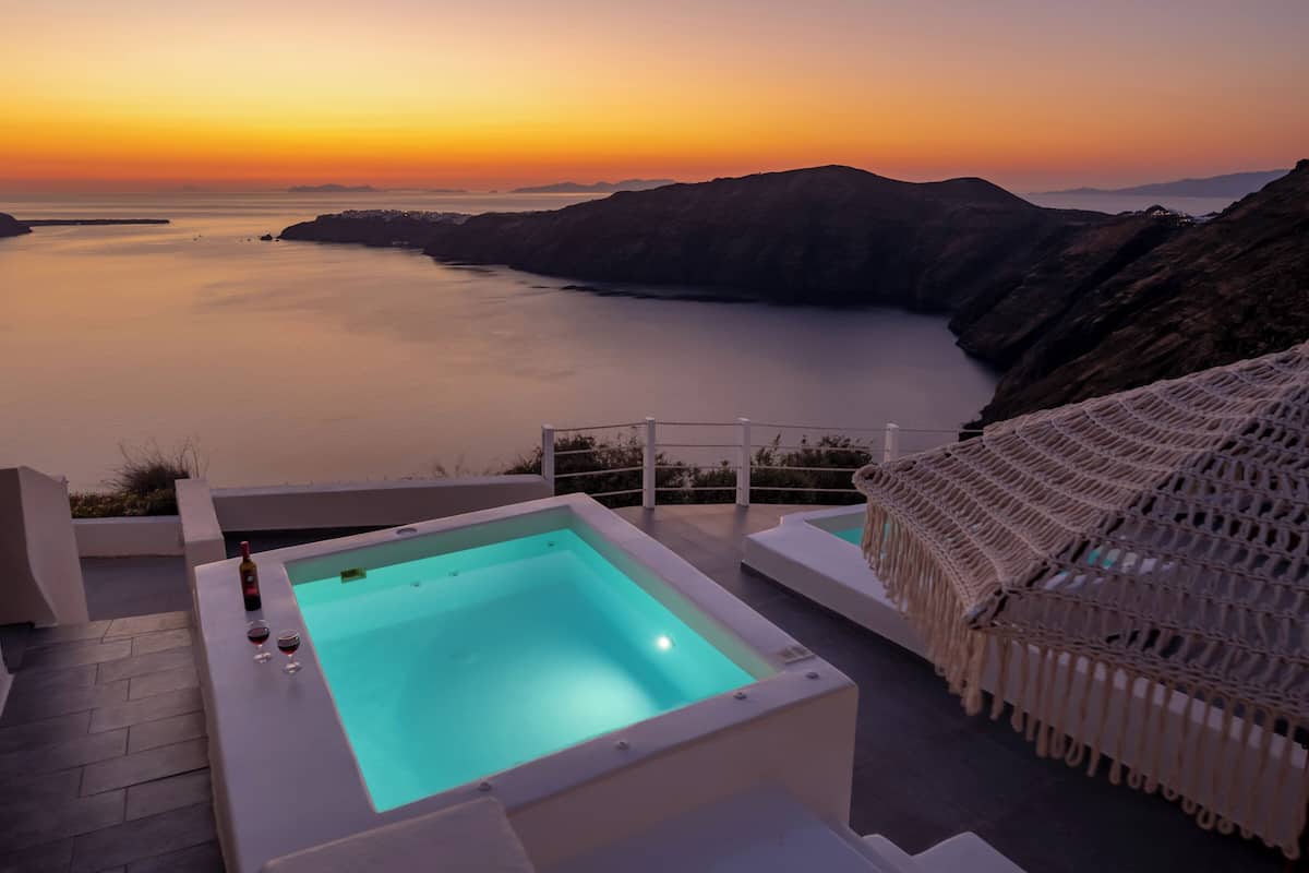 A pool with a sunset view, a bottle of wine, and a chair.