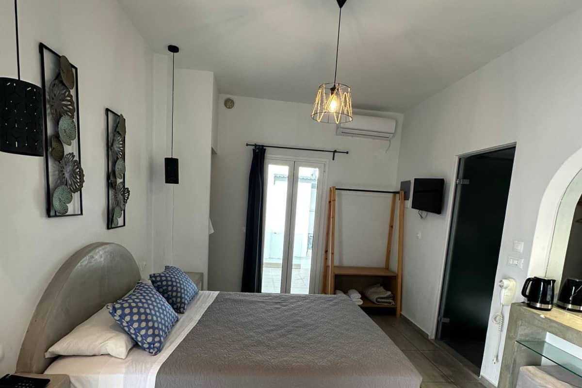 A bedroom with a bed, a bedside table, a lamp, a wardrobe, and a door.