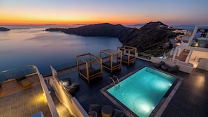 Una piscina en la azotea con vista al mar y a las montañas al atardecer.