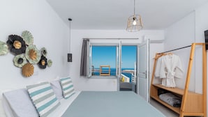 Un dormitorio con cama, armario de madera, vista al mar y una lámpara de techo.