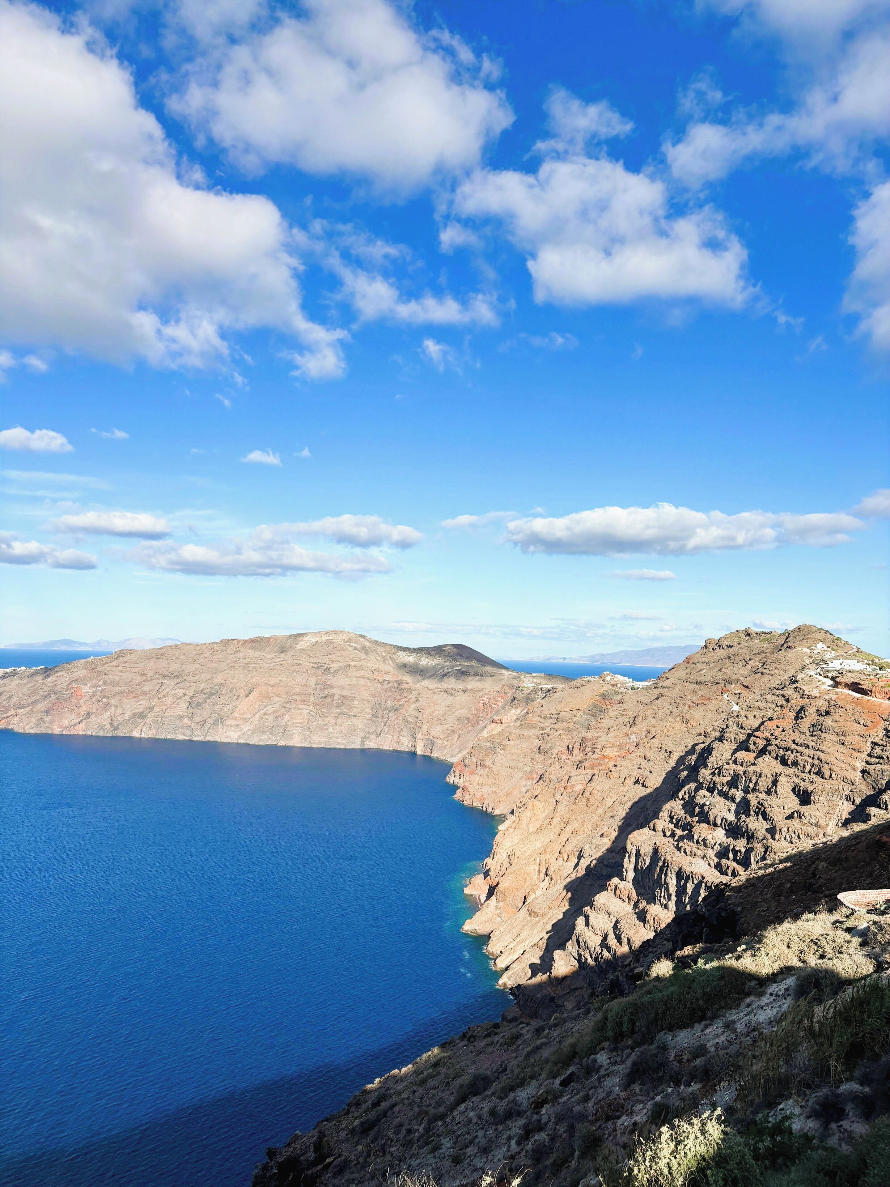 A coastal landscape with rugged terrain and a clear blue sea.