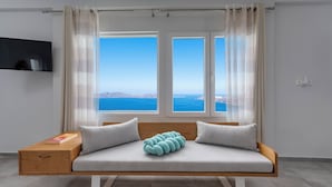 Una habitación moderna con sofá cama, televisión y vista al mar.