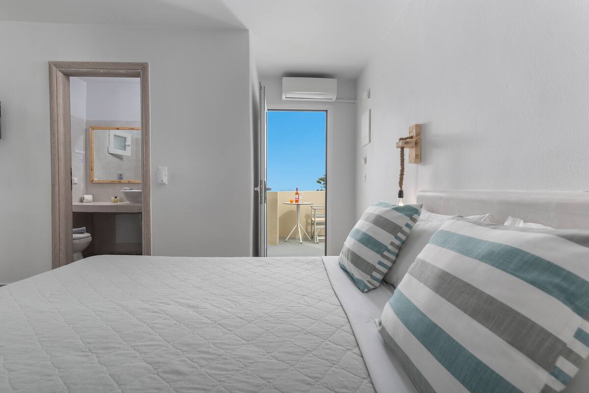 A hotel room with a bed, a bathroom, and a view of the outside.