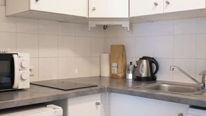 A kitchen with white cabinets, a microwave, a kettle, and a coffee maker. - Cosy studio in the heart of Bastille - Peace, comfort and Parisian spirit (Paris)