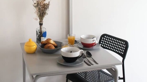 A breakfast setup with croissants, a vase of dried flowers, and a glass of orange juice on a table. - Cosy studio in the heart of Bastille - Peace, comfort and Parisian spirit (Paris)