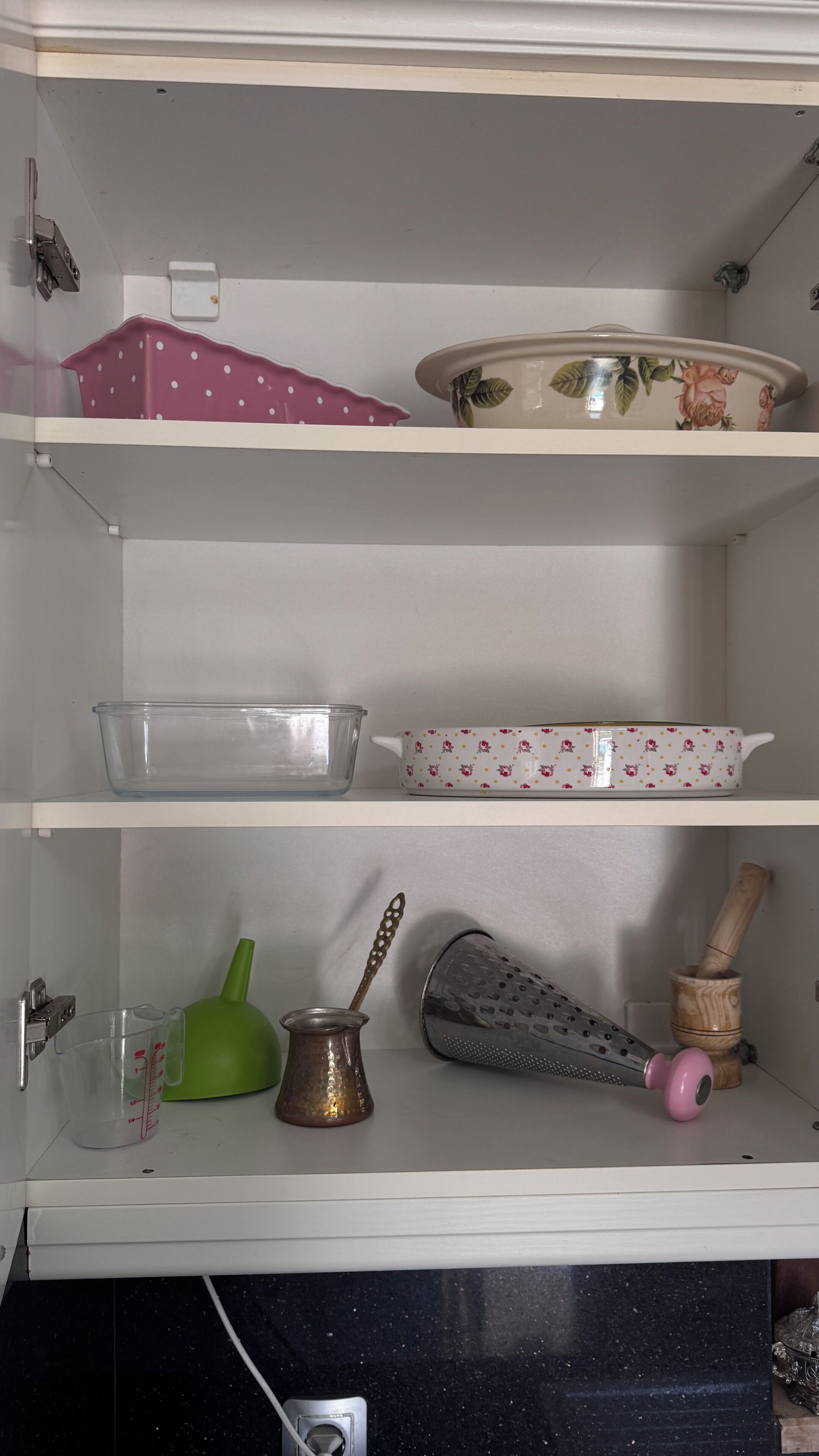 A kitchen cabinet with shelves holding various kitchenware items.