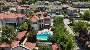 A residential area with multiple houses, a swimming pool, and a well-maintained lawn. - Villa Turaman Dalyan: Large 4-Bedroom House, Pool, Jacuzzi, Garden. Sleeps 10 (Muğla)