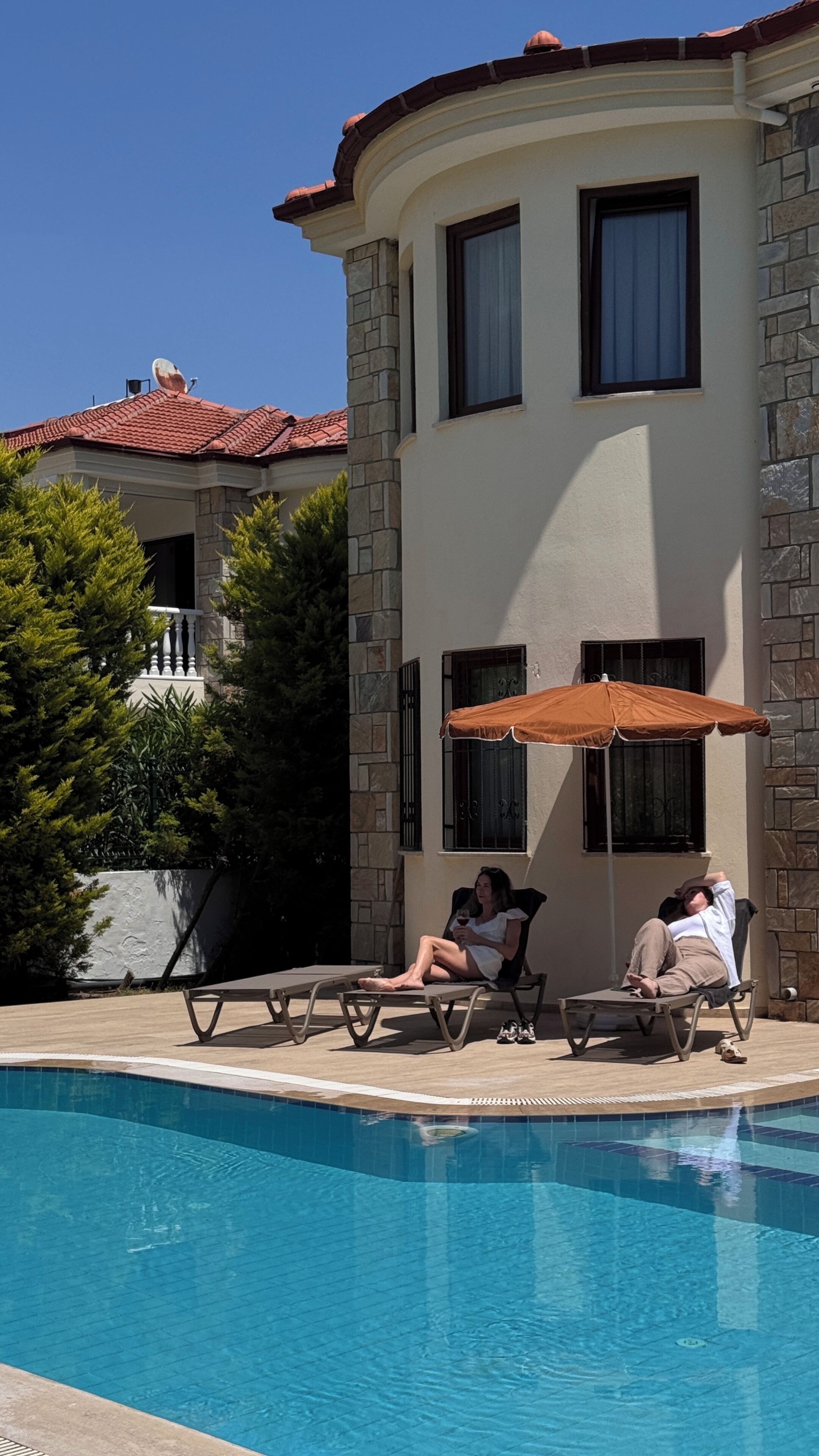 Un espace aménagé au bord de la piscine, avec des chaises longues et une personne qui se détend.