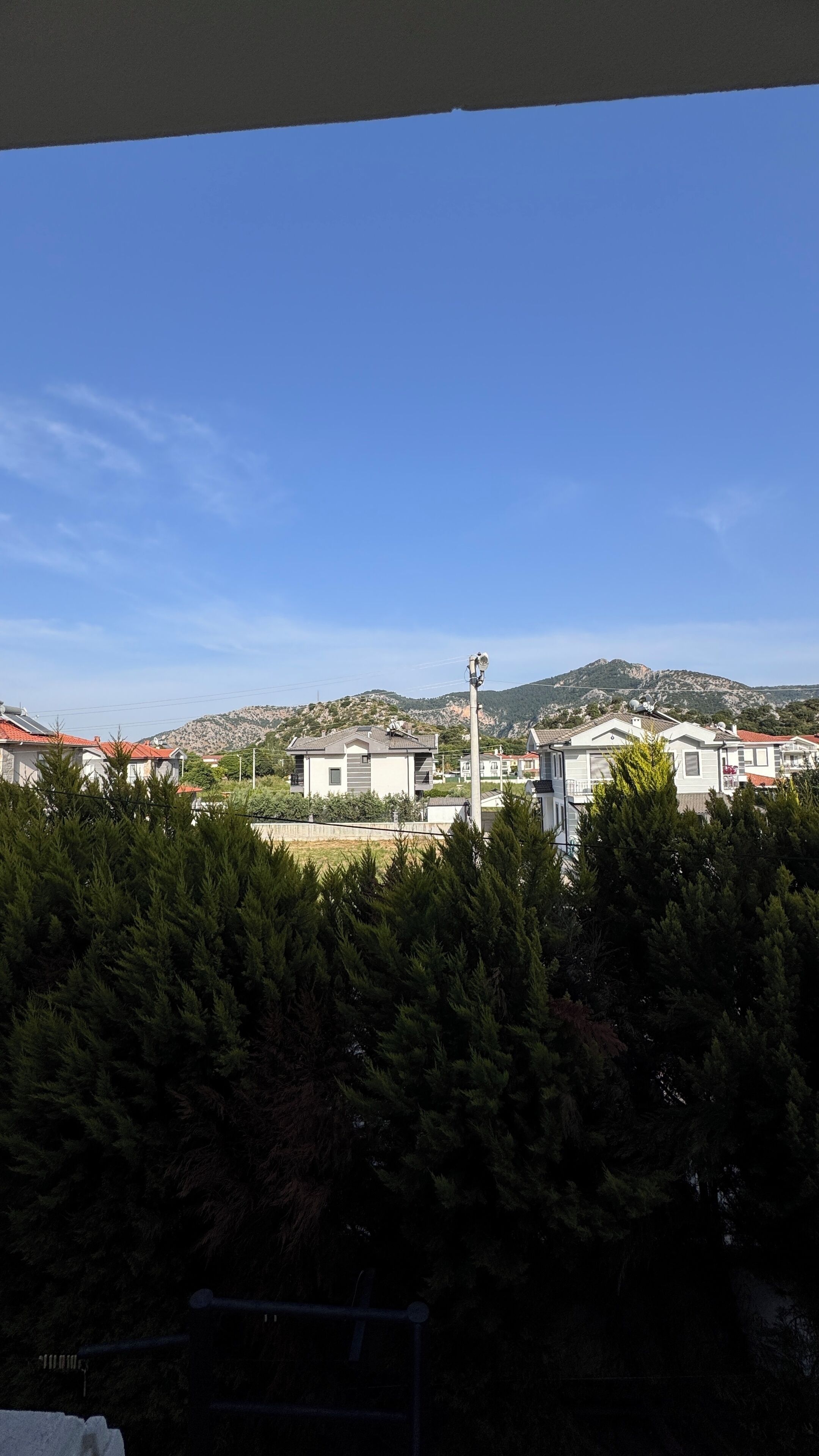 Zona residencial con casas, un poste de luz y un paisaje montañoso al fondo.