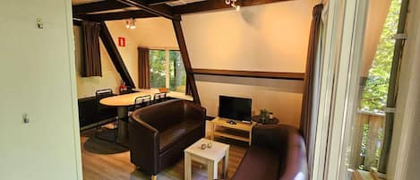 Un salon équipé d’un téléviseur, de deux canapés, d’une petite table et d’un coin repas avec une table et des chaises.