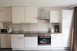A compact kitchen with white cabinets, a microwave, a coffee maker, and a built-in oven.