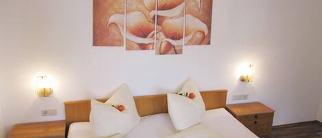 A double bed with white bedding, two nightstands, and a wall-mounted light fixture.
