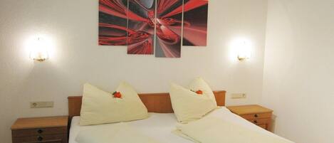 Una habitación de hotel con una cama, dos mesitas de noche, una obra de arte en la pared y dos luces de pared.