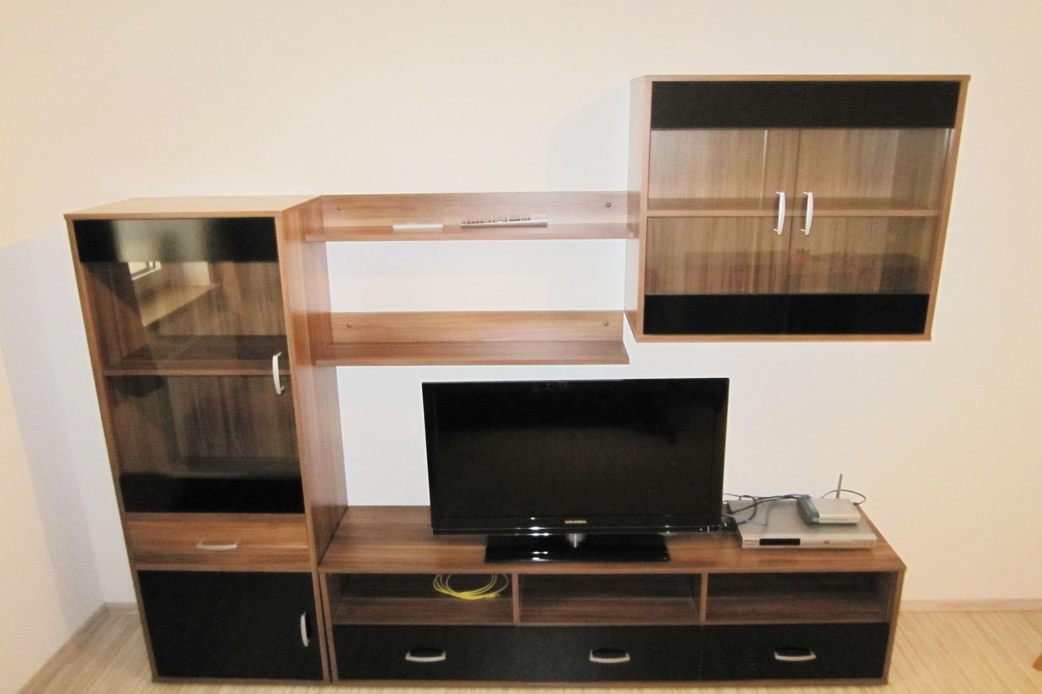 Un mueble de madera con un televisor de pantalla plana, un control remoto y una laptop encima.