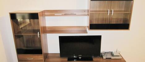 Un mueble de madera con un televisor de pantalla plana, un control remoto y una laptop encima.