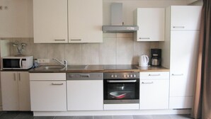 A compact kitchen with white cabinets, a microwave, a coffee maker, and a built-in oven. - Apartment in Kappl including Silvretta Card (Kappl)