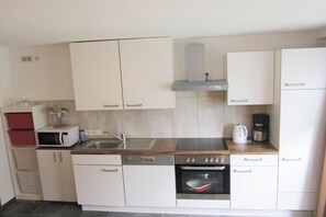 A compact kitchen with white cabinets, a microwave, a sink, a coffee maker, and a built-in oven. - Apartment in Kappl including Silvretta Card (Kappl)