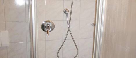 A shower with a handheld hose and a wall-mounted control.