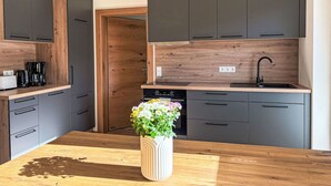 Una cocina moderna con armarios grises, encimera de madera, estufa integrada y un lavamanos.