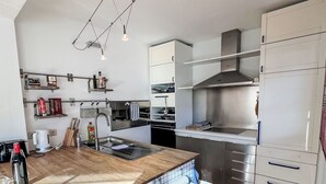 Eine moderne Küche mit Edelstahlgeräten, einer Holzarbeitsplatte und einem eingebauten Backofen.