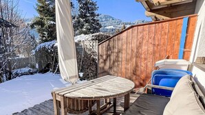 Eine Holzterrasse mit einem runden Tisch, einem Stuhl, einer blauen Kühlbox und einem Holzzaun.