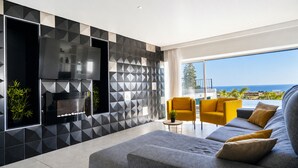 Ein modernes Wohnzimmer mit einem großen Fernseher, einer Couch und gelben Sesseln.