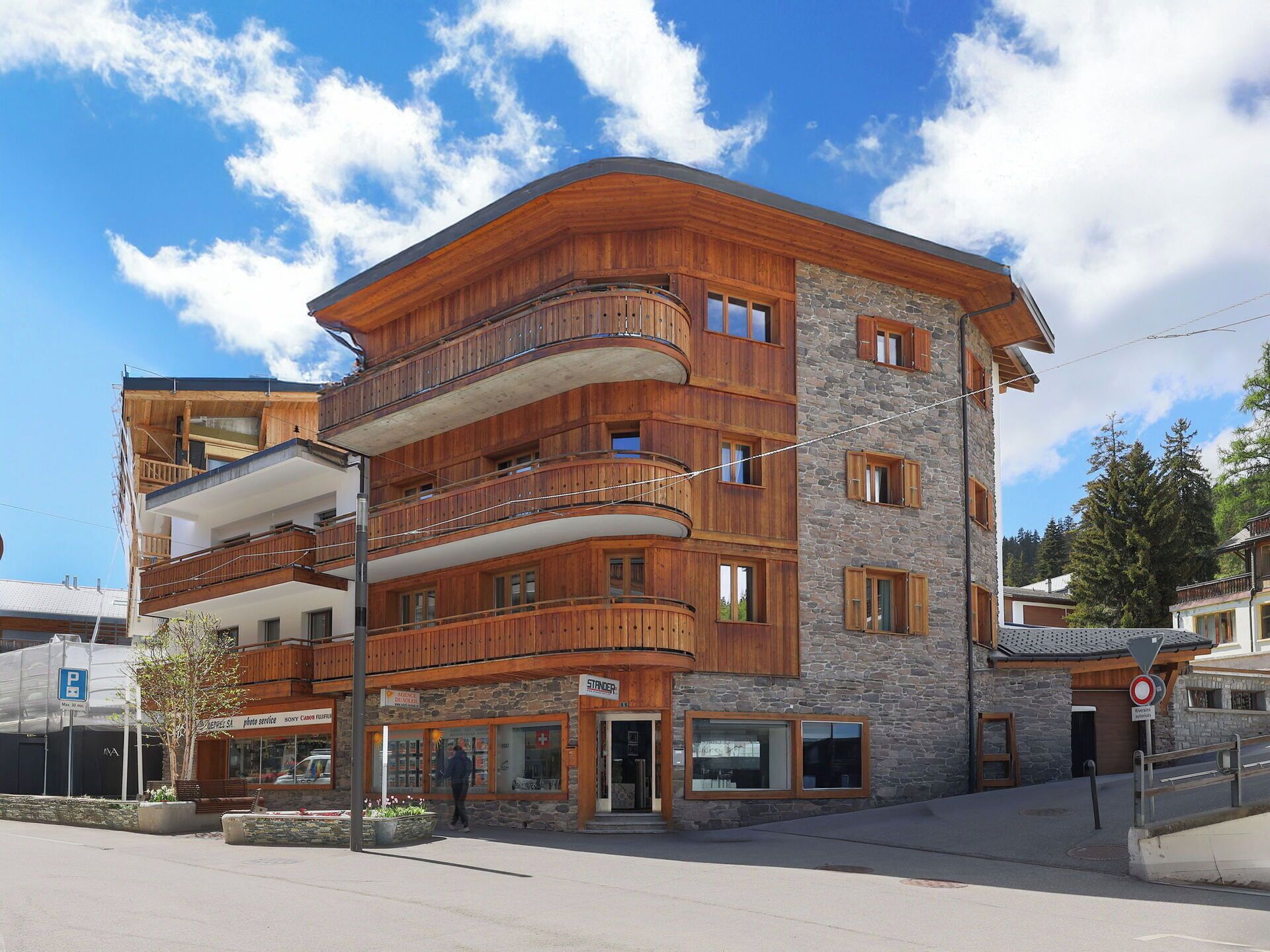 Un edificio a più piani con balconi in legno, facciata in pietra e un'insegna che indica un servizio fotografico.