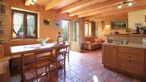Ein Holzblockbau-Innenraum mit Essbereich, einer Couch und einer Küche mit Fliesenboden.