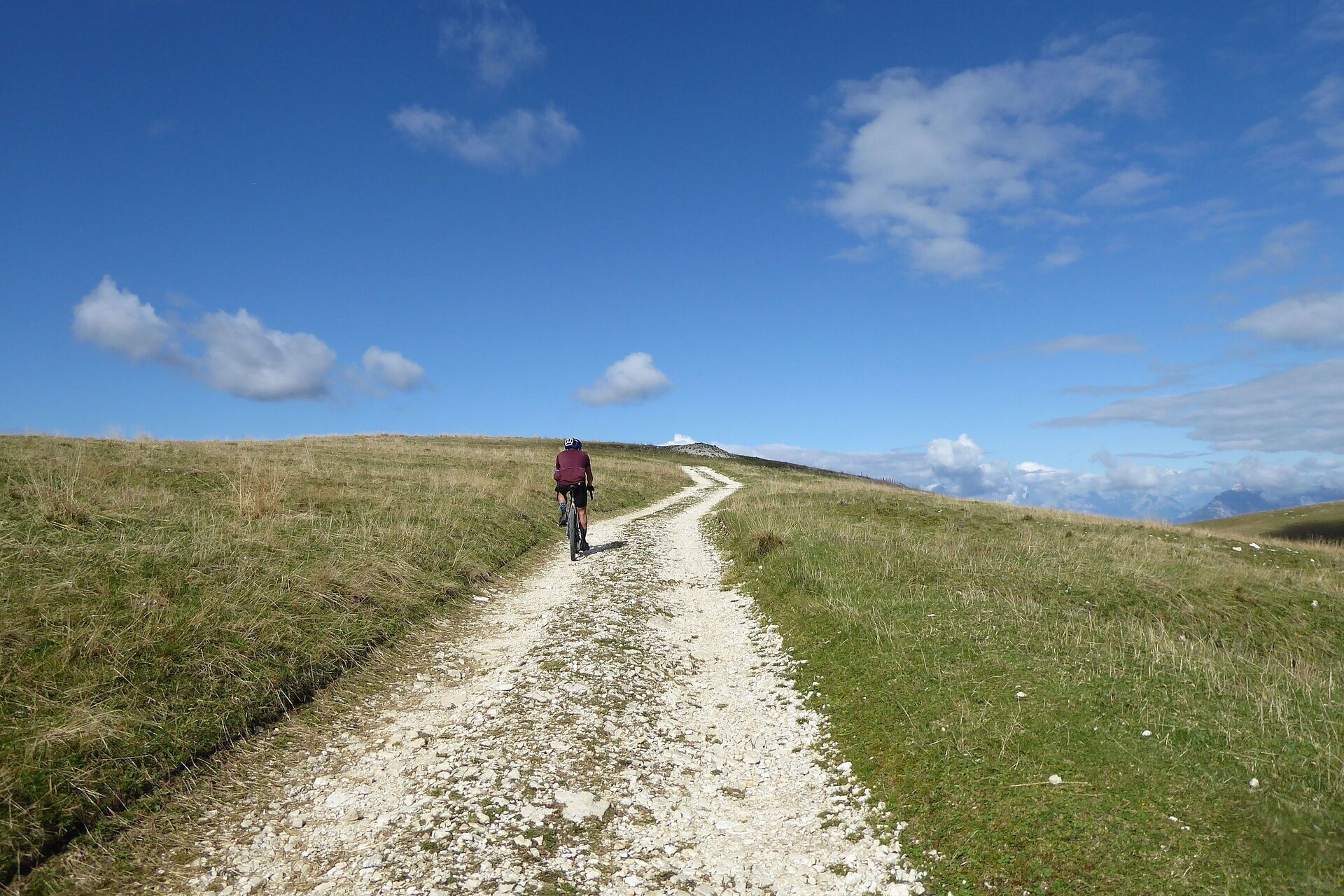 Ein Kiesweg auf einem grasbewachsenen Hügel unter blauem Himmel.
