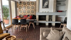 Una sala moderna con chimenea, un comedor con mesa y sillas, y un sofá.