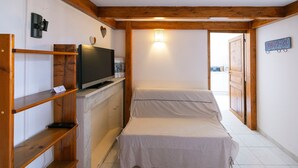 Un dormitorio con una cama, un televisor sobre una cómoda y un pasillo que conduce a otra habitación.