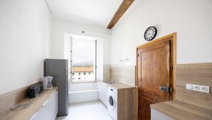 Una cocina compacta con lavadora, cafetera y un reloj en la pared.